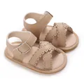 Detailed macro view of stylish baby girl sandals with scalloped strap and buckle - Apricot