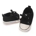 Close-up of black and white baby canvas sneakers with soft soles and laces - Insole Length 11cm / Black