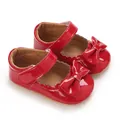 Detailed view of red patent leather baby girl Mary Janes featuring a decorative bow - Red