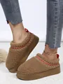 Gros plan de bottines de neige à plateforme en sherpa marron pour femme avec surpiqûres. - Marron