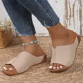 Detailed view of women's minimalist beige peep toe wedge mule slippers on straw mat - Apricot