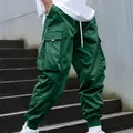 Close-up of green cargo pants featuring multiple utility pockets and elastic cuffs - Dark Green