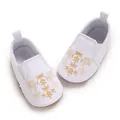 Detailaufnahme der weißen Baby-Lauflernschuhe mit feiner goldener Blumenstickerei auf Canvas - Weiß