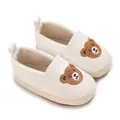 Detailopname van witte baby-loopschoenen met schattig bruin cartoonbeerborduurwerk en textuur. - Wit