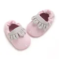 Primer plano detallado de zapatos de bebé rosas con suela blanda y volantes grises - Rosa