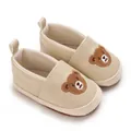 Close-up van beige baby loopschoentjes met schattig geborduurd beertje op de voorkant - Abrikoos