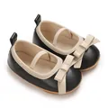 Close-up of black baby girl Mary Jane shoes with beige bow details and elastic strap. - Black