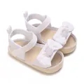 Detalle de sandalias blancas para bebé niña con lazo decorativo y cierre de velcro - Blanco