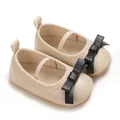 Close-up view of elegant cream baby girl sandals featuring a stylish black leather bow - Apricot