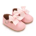 Gros plan de chaussures de princesse pour bébé en similicuir rose avec nœud et bords festonnés. - Rose
