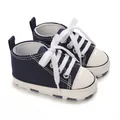 Close-up of navy blue baby canvas sneakers with white laces - Blue