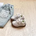 Grau-weiße Retro-Kinderschuhe mit weicher Gummisohle auf einem hellen Holzboden. - Größe 16 (Innenlänge 12cm) / Grau