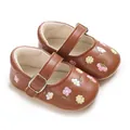 Vista detallada de zapatos Mary Jane marrones para bebé con delicados bordados florales. - Marrón Oscuro