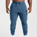 Detail view of men's blue jogger sweatpants with tapered cuffs and drawstring. - Blue
