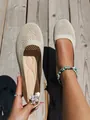 Detail view of breathable beige knit round toe flat shoes for women on wooden deck - Off White
