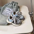 Primo piano di scarpe da ginnastica per bambini blu e grigie accanto a jeans blu - Blu