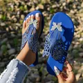 Vista detallada de chanclas planas azules con diseño de mariposa de strass brillante. - Azul