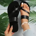 Detail view of black flat toe-loop sandals with stylish leather straps for summer beach. - Black