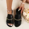 Detailed view of women's black crocodile-embossed flat slides with chic gold chain accents - 36 / Black