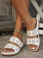 Detailed view of white flat slides with laser-cut floral patterns on double straps. - White