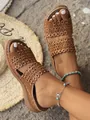 Close-up detail of retro brown flat sandals with intricate hollow flower cutout patterns - Brown