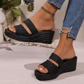 Detail view of black wedge sandals featuring braided and leopard print straps on feet. - Leopard + Weaving