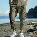 Detailed view of men's olive cargo pants with drawstring waist and side pockets on beach - S / Bottoms / Army Green