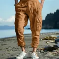 Men's brown cotton linen cargo pants with drawstring waist and pockets on beach - Earthy Yellow