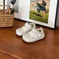 Gros plan de baskets crème pour tout-petits avec bandes velcro sur du bois. - Khaki