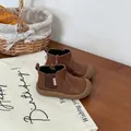 Close-up of brown children's leather Chelsea boots on a rustic wooden table setting. - Brown