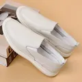 Nahaufnahme von cremeweißen Leder-Slippern mit weichen Sohlen und feinen Nähten - Weiß