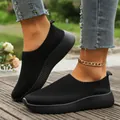 Detail view of breathable black knit sneakers for women on feet with stylish ankle chain - 36 / Black