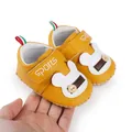 Dettaglio di scarpine gialle per neonati con design a coniglietto e chiusura a strappo. - Giallo