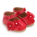 Primer plano detallado de zapatos de princesa rojos para bebé con flores y perlas. - Rojo