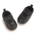 Primo piano di scarpe primi passi per neonati in ecopelle nera con chiusura a strappo - Nero