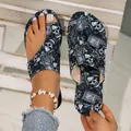 Detailed view of women's flat sandals featuring a gothic skull and RIP pattern print - Black