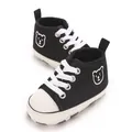 Gros plan de baskets en toile noires pour bébé avec broderie ours et semelles souples - Noir