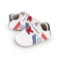 Detailansicht von weißen Baby-Lauflernschuhen mit roten Schnürsenkeln und blauen Streifen - Rot