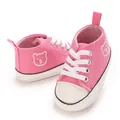Gros plan sur les chaussures de marche roses pour bébé avec broderie d'ours mignon - Rose
