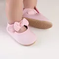 Detailaufnahme von rosa Baby-Prinzessinenschuhen mit Schleife und rutschfesten Sohlen. - Rosa