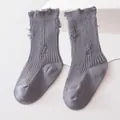 Detail view of grey ribbed distressed socks for children with ruffled tops - Gray