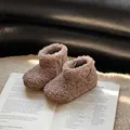 Bottines confortables en fausse fourrure pour bébé sur un livre - Abricot