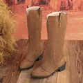 Detailed view of brown suede tall boots with pointed toe and block heel on wooden floor - 36 / Brown