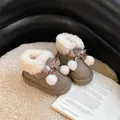 Detailed view of cozy girl's brown snow boots with fur lining and cute pink bows. - Antelope Brown