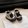 Detailed close-up of quilted beige baby winter boots with black laces and soft soles. - Black