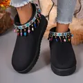 Detail view of black snow boots featuring vibrant ethnic embroidery and beaded tassels. - Black