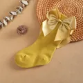 Detalle de un calcetín alto para bebé color jengibre con un gran lazo de satén decorativo. - Amarillo jengibre