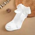 Close-up of white children's knee-high socks featuring a large decorative satin bow - 0-1 Years / White