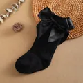 Close-up detail of black children's knee-high socks featuring a large elegant satin bow - 0-1 Years / Black