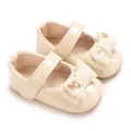 Dettaglio di scarpe Mary Jane beige per neonati con fiocco e decorazione dorata - Albicocca